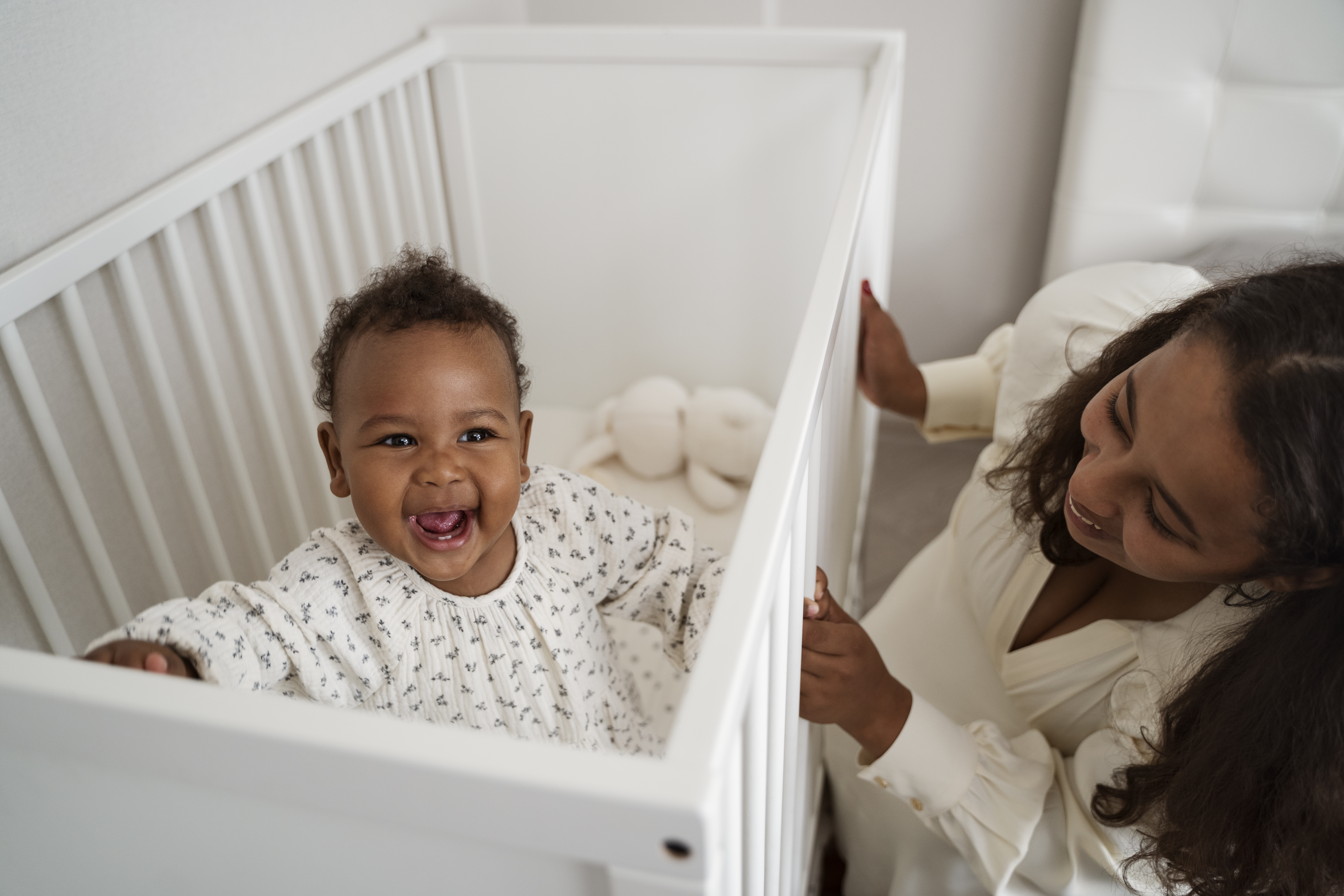 bebê no berço branco e mãe felizes e sorrindo